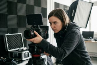 Étudiante en formation audiovisuelle réglant une caméra professionnelle dans un studio équipé